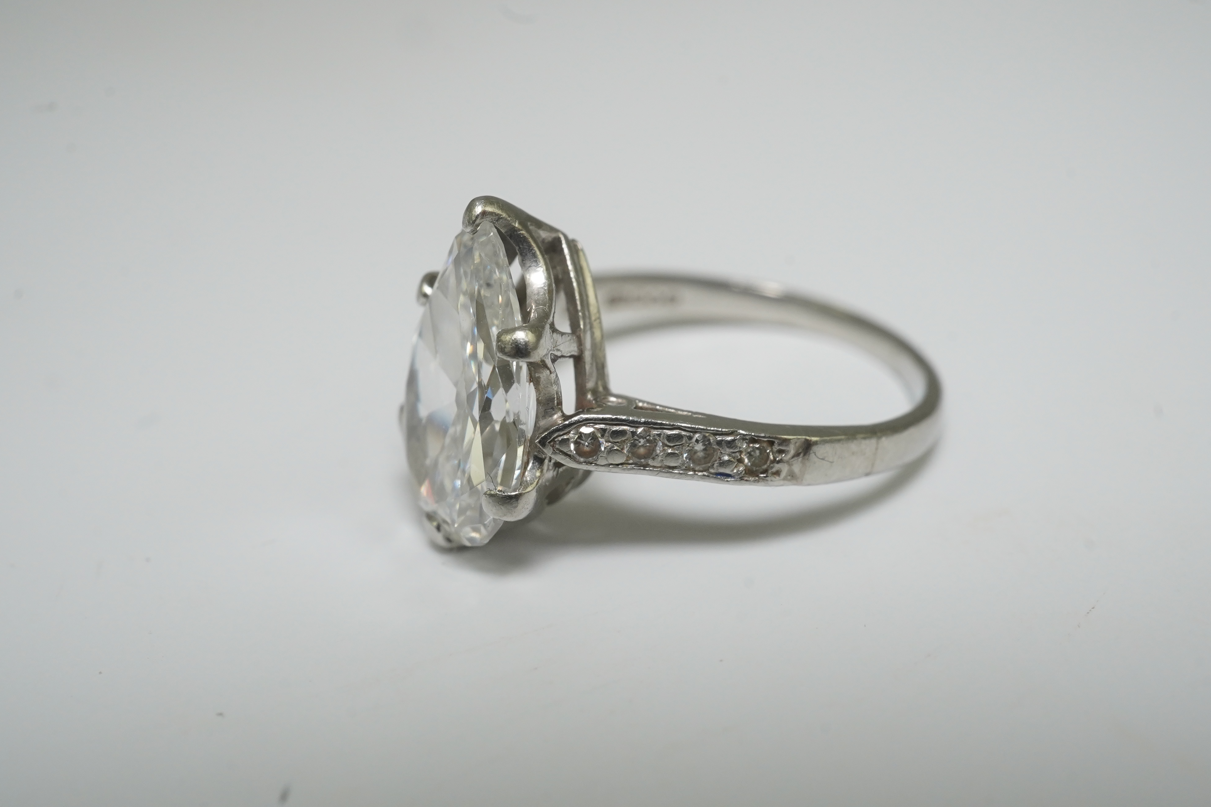 A platinum and pear cut single stone diamond set ring, with diamond set shoulders